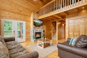 Ein Holzblock-Interieur mit Kamin aus Stein, einem Fernseher, einer Treppe und einer großen Holztür.