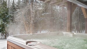 Ein Whirlpool, umgeben von schneebedeckten Bäumen.