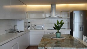 A modern kitchen with white cabinetry, a central island with a plant, and a stainless steel refrigerator. - Loft in Quito with the best view and location !!! (Quito)
