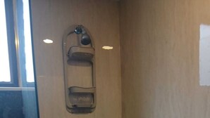 A small, enclosed shower area with a wooden wall, a glass door, and a metal showerhead. - Loft in Quito with the best view and location !!! (Quito)