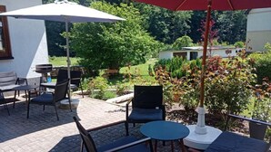 An outdoor patio with a table and chairs, a grill, and a red umbrella. - Your idyllic guest house on the Hexenstieg in the Bode Valley (Thale)