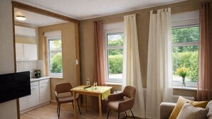 A cozy room with a wooden floor, a dining table with chairs, a sofa, and a TV. - Your idyllic guest house on the Hexenstieg in the Bode Valley (Thale)