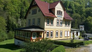 A two-story building with a red-tiled roof, a sign reading "Hotel," and a small attached structure with a glass front. - Your idyllic guest house on the Hexenstieg in the Bode Valley (Thale)