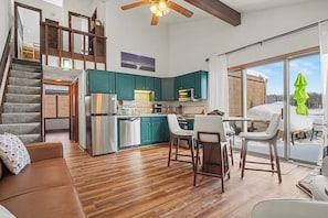 A spacious kitchen with wooden floors, teal cabinets, and a dining area with white chairs. - Cozy 3-bedroom home near Boyne, Otsego, and Treetops - Full of Amenities (Gaylord)