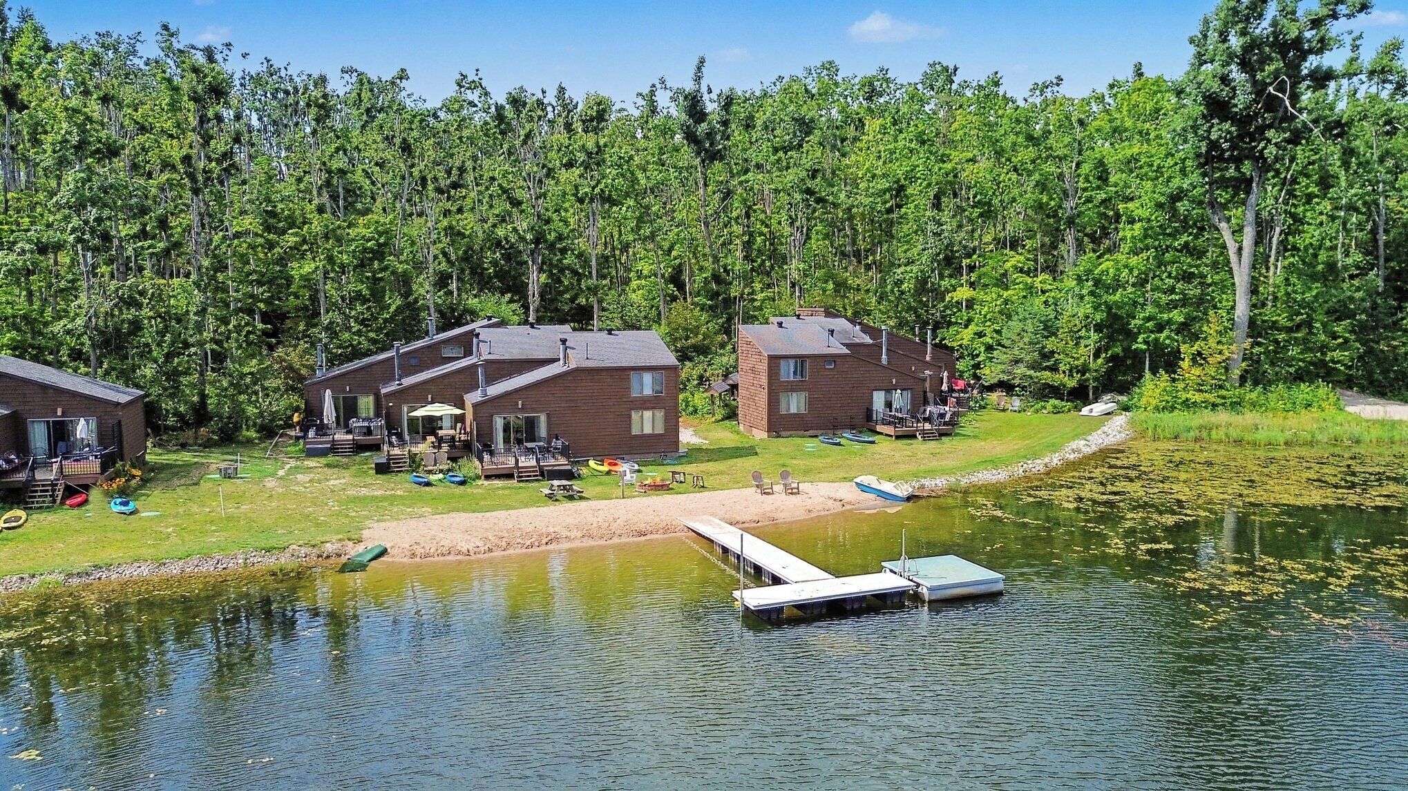 A lakeside cabin area with multiple buildings, a dock, and boats.