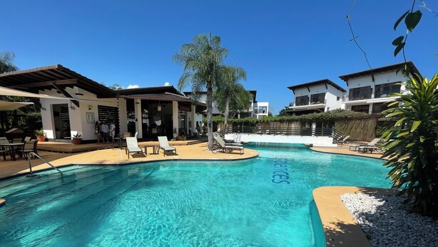 A swimming pool with clear blue water, surrounded by lounge chairs and a restaurant named "Concourse." - Serene Tropical Hideaway: Private Patio & Pools (Playa Juan Dolio)