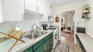 A modern kitchen with white cabinets, a herringbone tile backsplash, and a wooden drying rack. - Downtown Perrysburg Bungalow w/ additional space (Perrysburg)