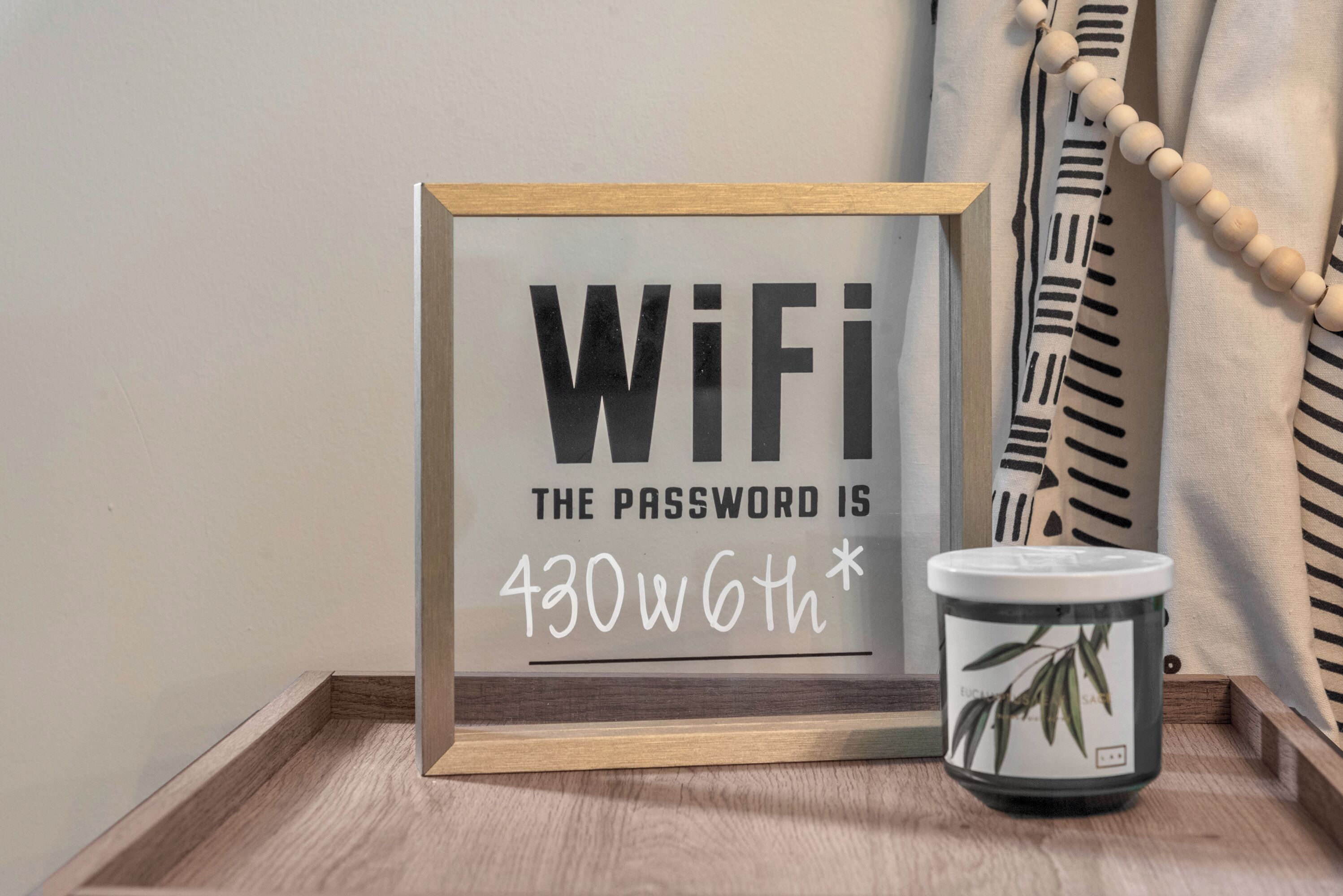 A framed sign with the text "WiFi: The password is 430w6th*".
