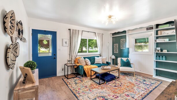 A living room with a blue door, a sofa with cushions, a coffee table, a patterned rug, and a bookshelf. - Downtown Perrysburg Bungalow w/ additional space (Perrysburg)