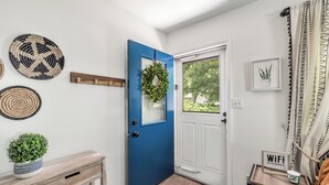 A hallway with a blue door, a white door, and a small table with a WiFi sign. - Downtown Perrysburg Bungalow w/ additional space (Perrysburg)