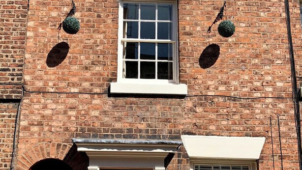 A brick building with a red door, two windows, and a small balcony. - Central Chester home. Excellent location. Sleeps 4. Pet friendly. (Chester)