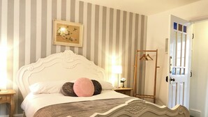 A neatly arranged bedroom with a bed, a bedside table, a hanging wardrobe, and a door. - Central Chester home. Excellent location. Sleeps 4. Pet friendly. (Chester)