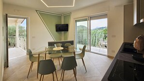 Een moderne keuken met een inbouwoven en een eethoek met een glazen tafel en stoelen.