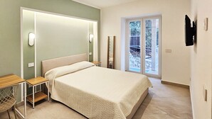 Een moderne slaapkamer met een groot bed, een bureau en een schuifdeur naar een buitenruimte.