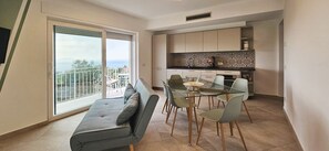 Un appartement moderne doté d’un balcon, d’un coin repas avec une table en verre et d’une cuisine avec un crédence décorée.