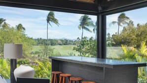 Un interior moderno con techo de madera, una zona de bar con taburetes y vistas a un campo de golf.