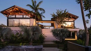 Una casa moderna con terraza de madera, ventanas amplias y un camino de piedra que conduce a la entrada.