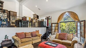 Amplia sala de estar con dos sofás, un reposapiés rojo y una escalera que sube a un nivel superior.