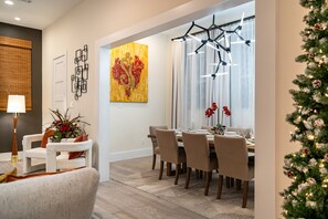 A dining area with a table set for four, a white chair, and a potted plant. - Twin Home: 8BR, Sleeps 20, 2 Rooftops Near Dtown (HOUSTON)