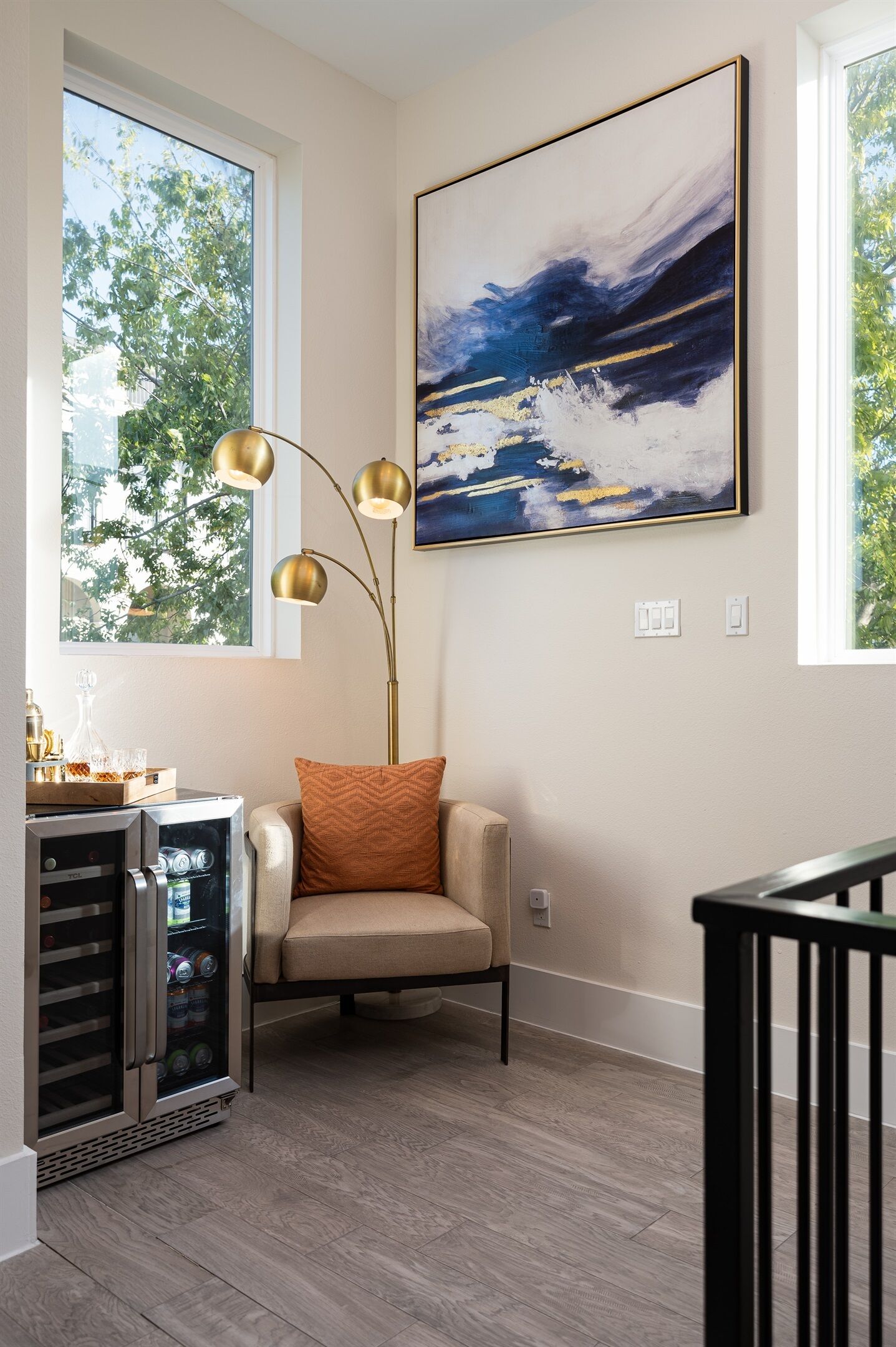 Una sala de estar moderna con un sillón color beige, una lámpara de pie y un cuadro abstracto grande en la pared.