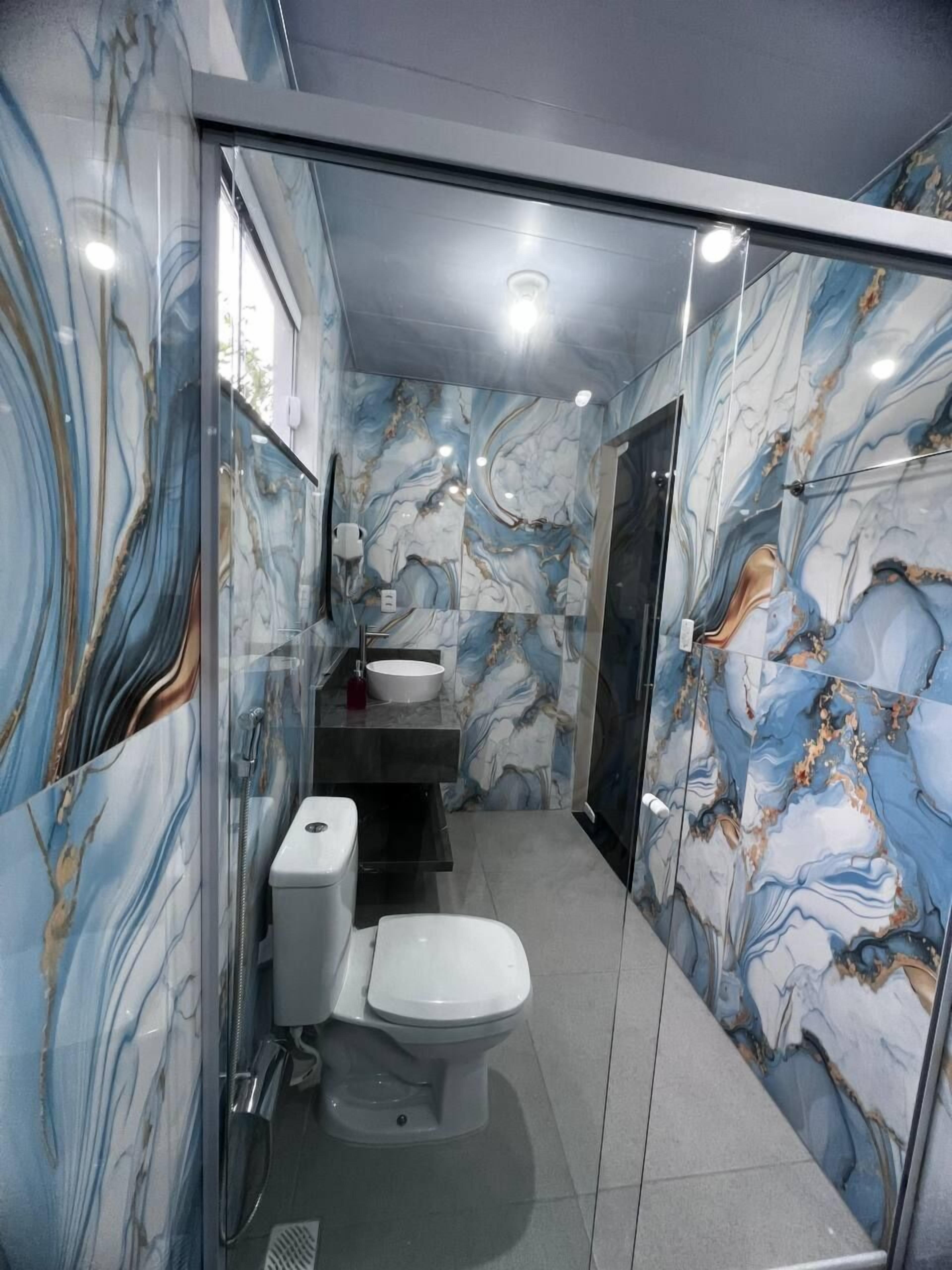 Un baño con diseño de mármol, un inodoro, un lavamanos y zona de ducha.