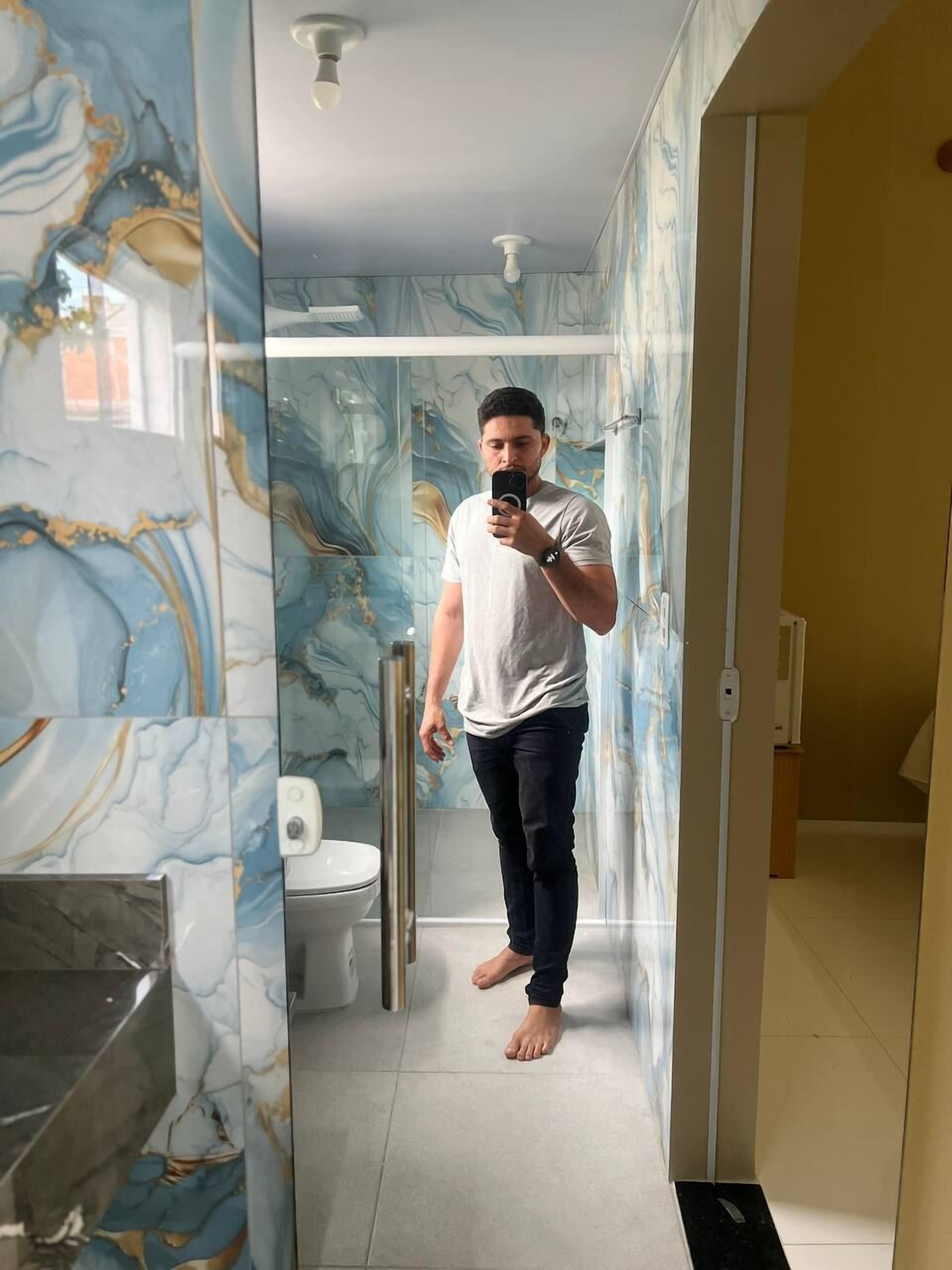 Een moderne badkamer met marmeren wanden, een glazen douchecabine en een zichtbaar toilet.
