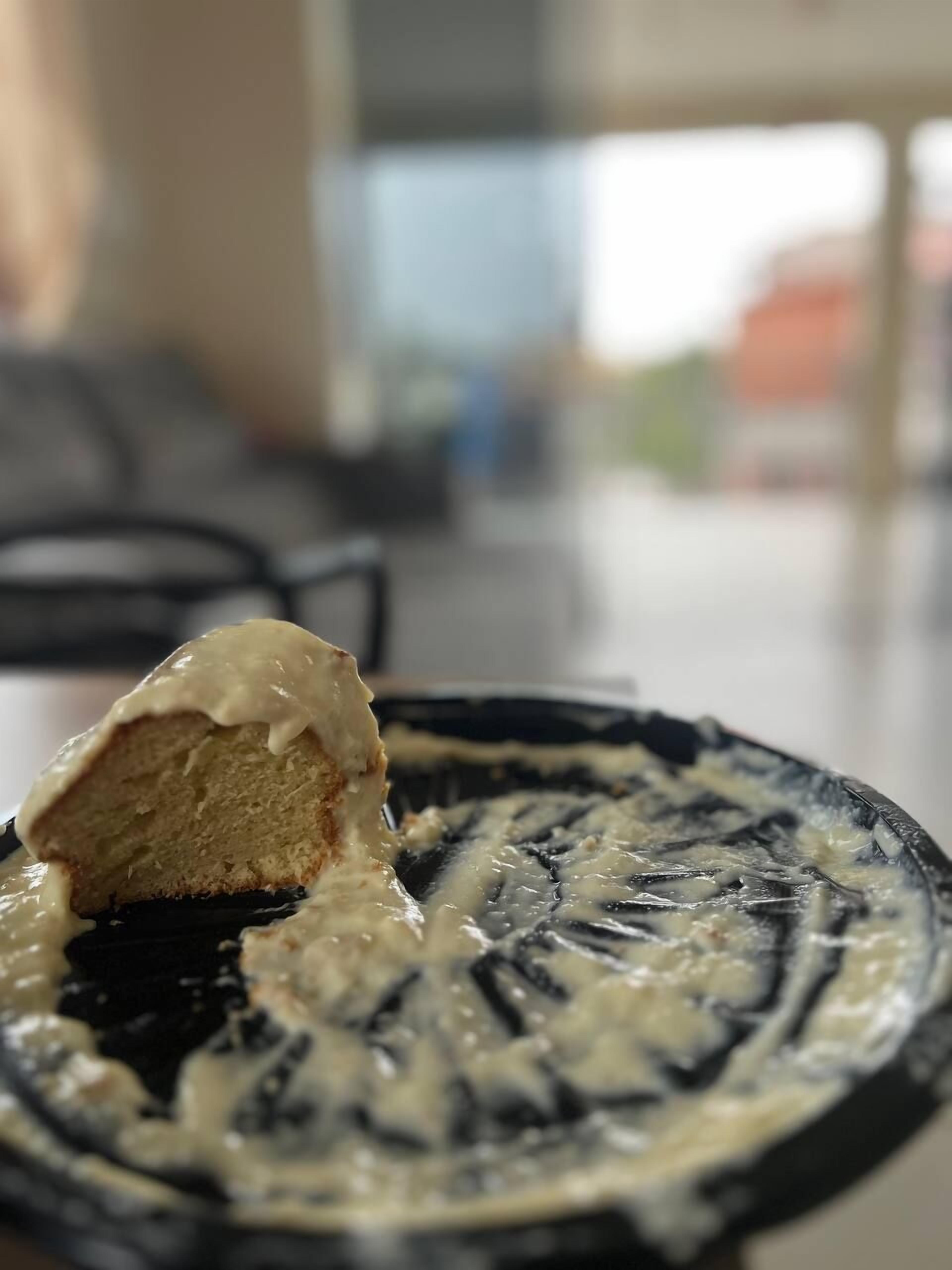 Una porción de pastel con cobertura blanca sobre un plato con diseño blanco y negro.