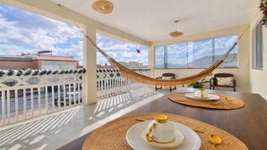 A spacious balcony with a hammock, dining table with placemats, and a view of the cityscape. - Lar dos  Lençoís bhs (Barreirinhas)