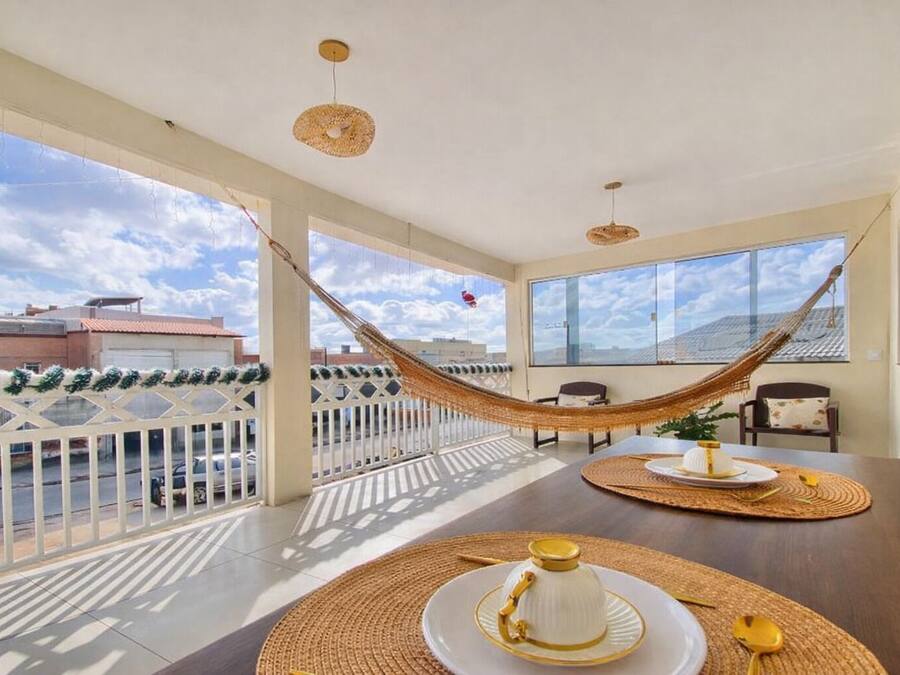 En rummelig balkon med hængekøje, spisebord med servietter og udsigt over bybilledet.