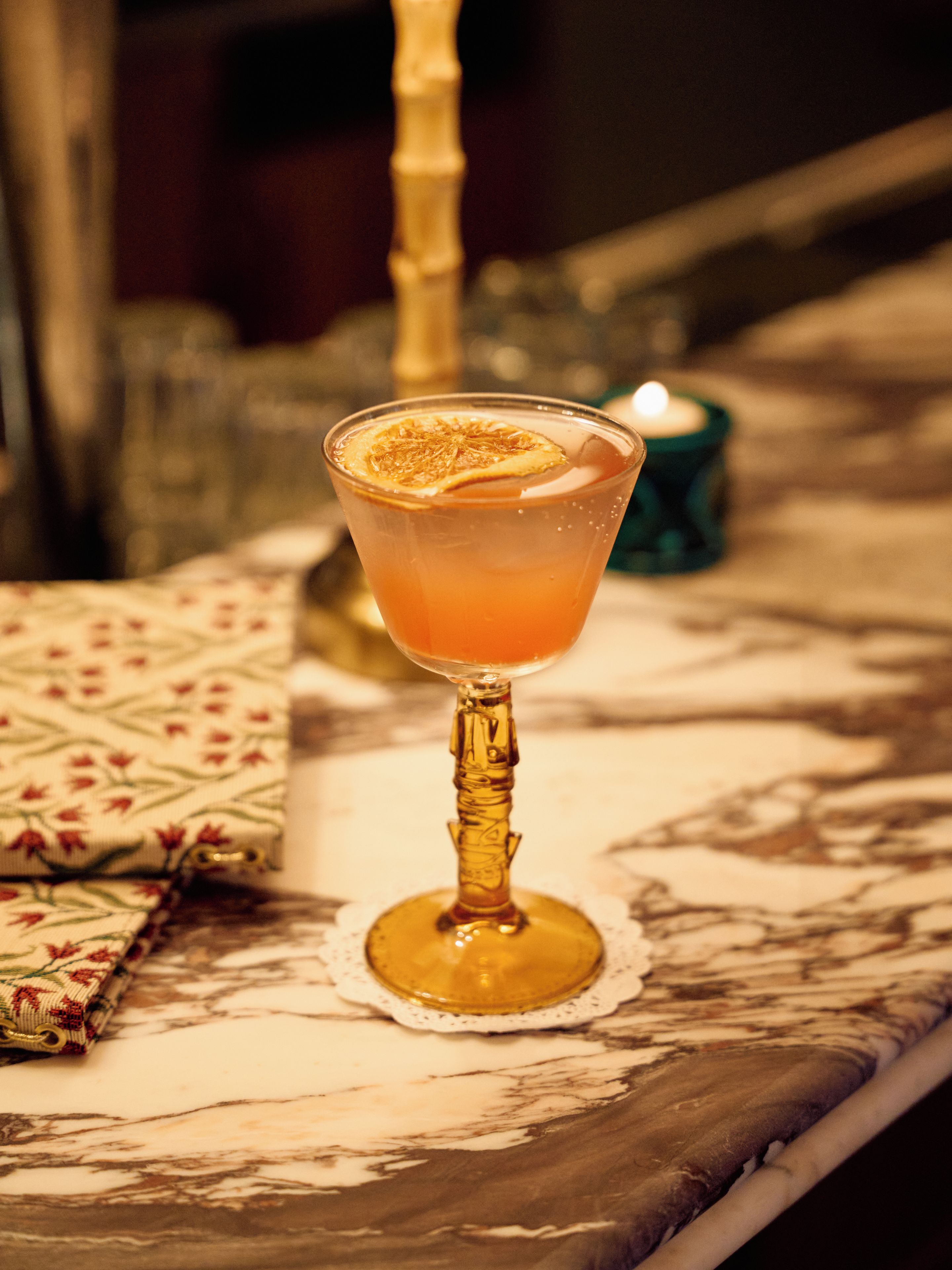 A cocktail glass with a garnish on a marble table.