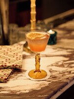Ein Cocktailglas mit einer Garnitur auf einem Marmortisch.