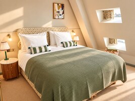 Ein ordentlich eingerichtetes Schlafzimmer mit einem Bett, Kissen, einem Nachttisch, einer Lampe und einem Wandbild.