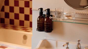 A bathroom with a white sink, two bottles of hand soap, a glass, and a mirror.