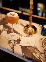 Ein Marmortisch mit einem Cocktailglas, einer Kerze und einer Speisekarte.