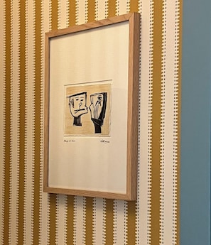 Ein gerahmtes Kunstwerk an einer Wand mit Streifenmuster.