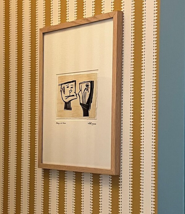 Ein gerahmtes Kunstwerk an einer Wand mit Streifenmuster.