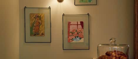A room with a bed, a lamp, and framed artwork on the wall.