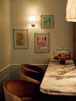 Ein Zimmer mit einem Bett, einer Lampe und gerahmten Kunstwerken an der Wand.