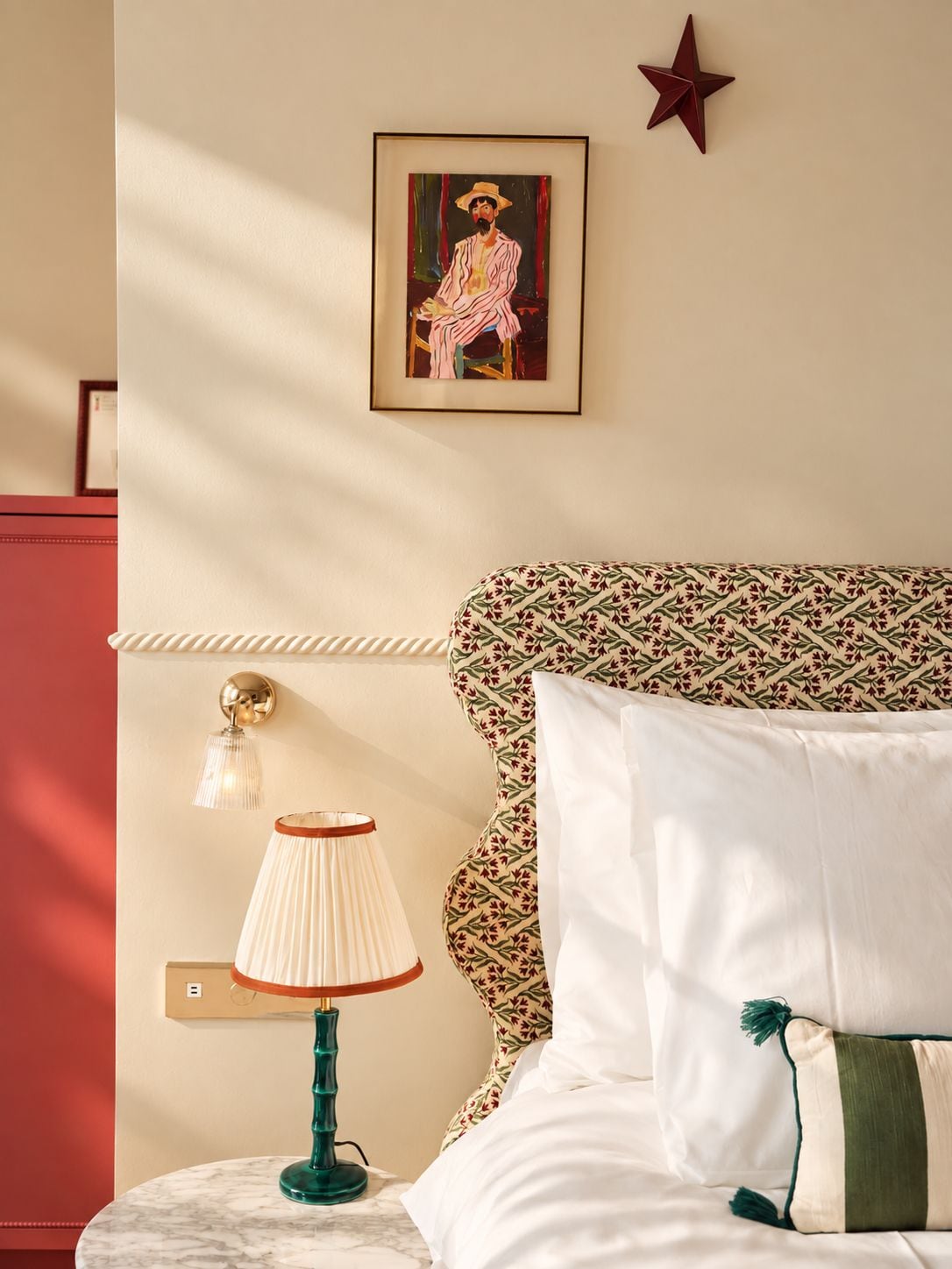 Un dormitorio con cama, mesita de noche con lámpara, un cuadro enmarcado en la pared y decoración con motivos de estrellas.