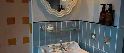 Ein Badezimmer mit einem weißen Waschbecken, einem großen Spiegel und zwei Seifenspendern an der Wand.