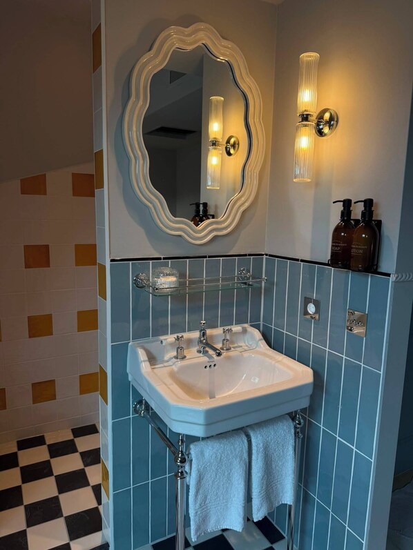 Ein Badezimmer mit einem weißen Waschbecken, einem großen Spiegel und zwei Seifenspendern an der Wand.