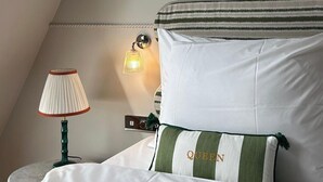 Une chambre à coucher avec un lit, une lampe, un luminaire fixé au mur, un tableau encadré et une décoration en forme d’étoile.