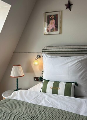 Ein Schlafzimmer mit einem Bett, einer Lampe, einer Wandleuchte, einem gerahmten Bild und einer Stern-Dekoration.