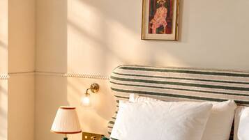 Habitación de hotel con cama, mesita de noche, lámpara, un cuadro enmarcado y un adorno con forma de estrella en la pared.