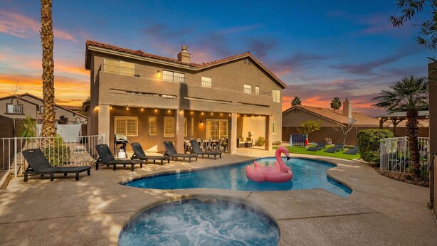 Une maison à deux étages dotée d’une piscine, d’un jacuzzi et d’un espace salon extérieur.