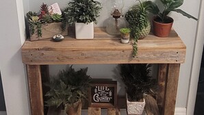 A wooden console table with potted plants and decorative items, including a sign that says "Life is better in the country." - Cozy Cottage Sleeps 8 close to the World Equestrian Center (Ocala)