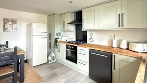 Een moderne keuken met witte kastjes, een houten aanrechtblad en een ingebouwde oven.