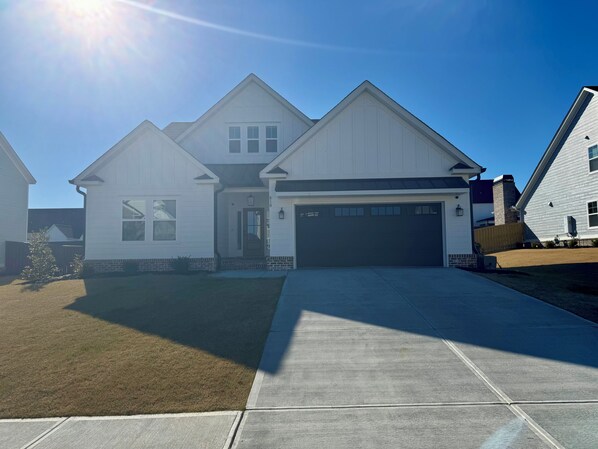 A two-story house with a garage, a well-maintained lawn, and a clear sky. - 2026 Masters Rental - 11 Miles from Augusta National (Evans)