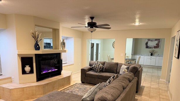 A living room with a fireplace, two sofas, a TV, and a ceiling fan. - Relaxed Desert Stay - 3BR/2BA Tucson Home - Furnished & Spacious (Tucson)