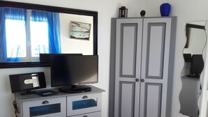 Ett sovrum med en säng, en byrå med lådor, en tv ovanpå och en garderob.